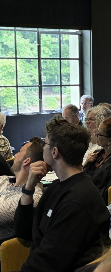 Das Publikum im Saal und ein stehender Mann der etwas sagt